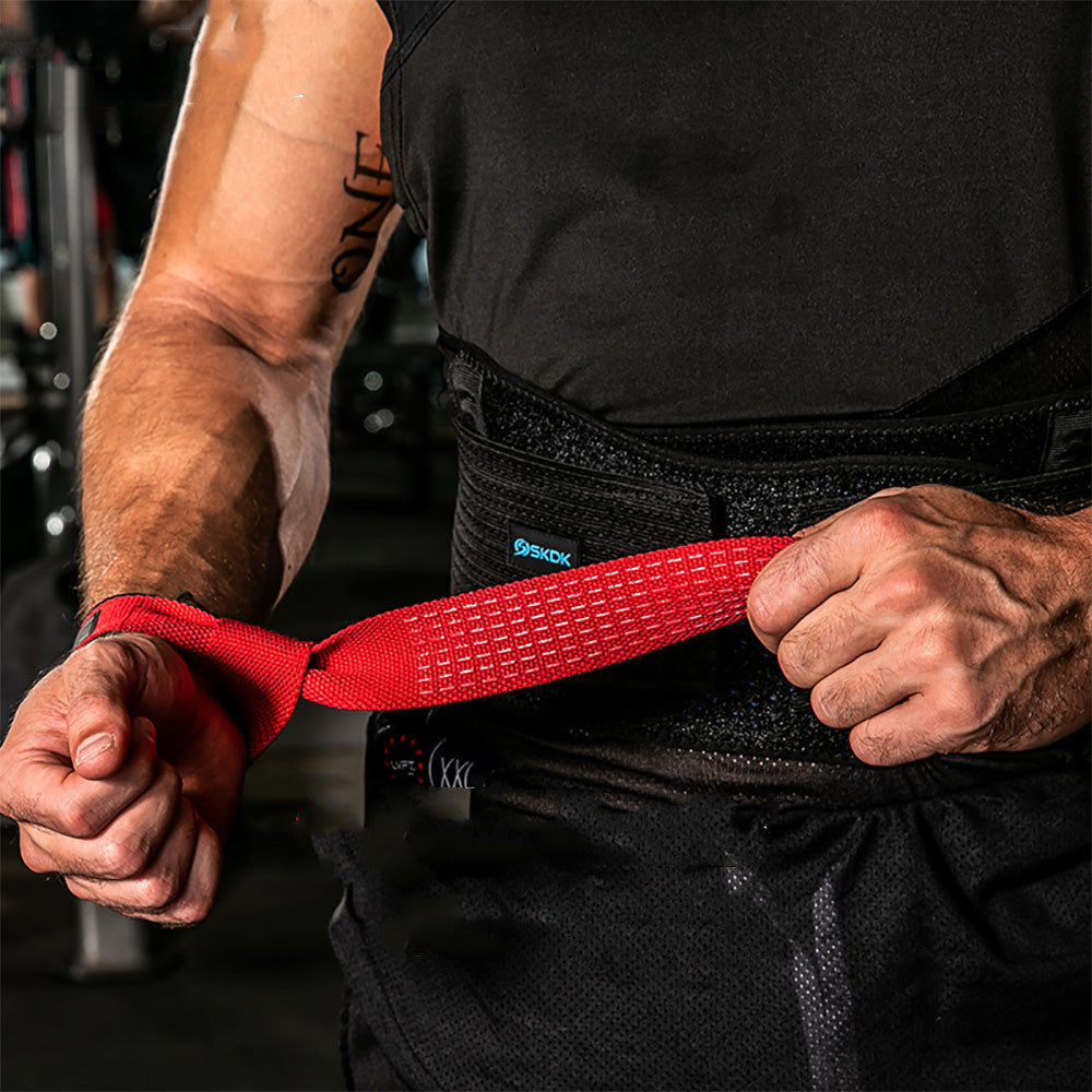 Person wearing a black weightlifting belt with a red strap, likely in a gym setting.